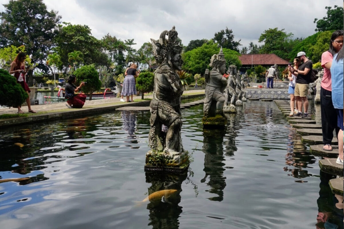 Tirta Gangga Water Palace fish pools, statues and crowds of people