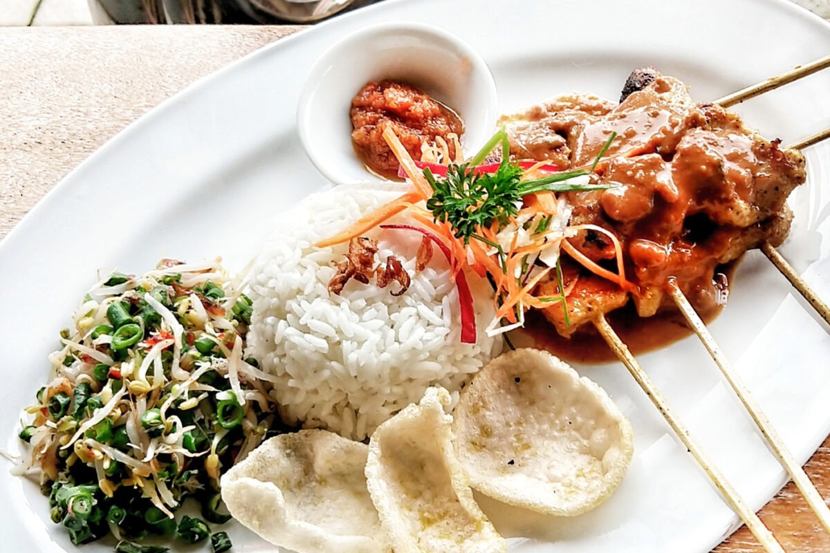 Food in ubud Bali from a warung, rice, satay skewers and prawn crackers with Balinese salad.