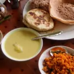 Sri Lankan breakfast foods on a table. Curry, hoppers, roti and coconut chutney.