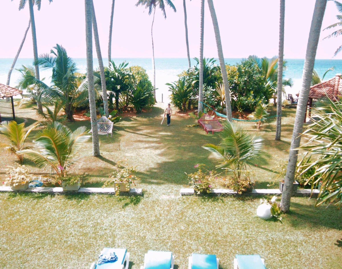 Beach view from the Max Wadiya, palm trees, hammocks and a child with a cricket bat.