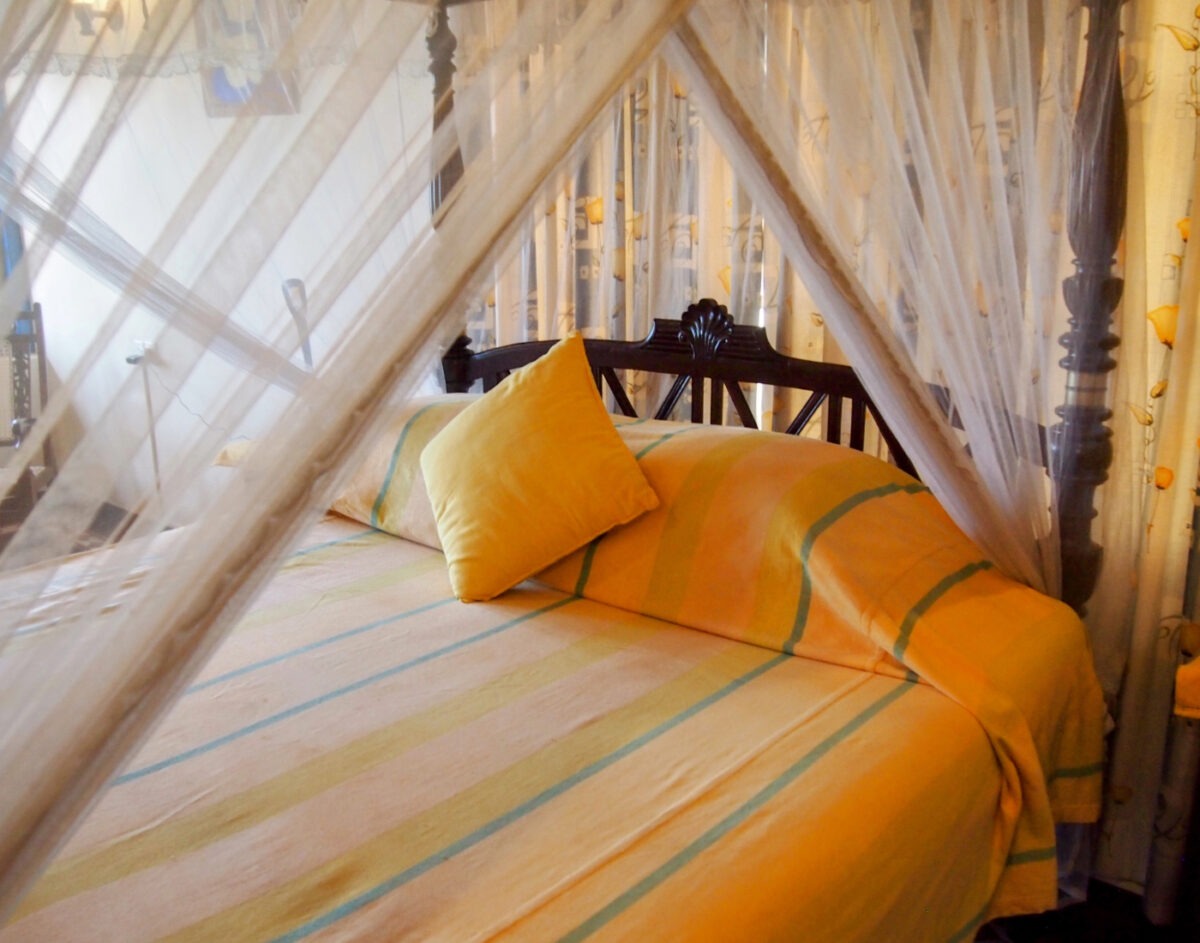 Bedroom with four posted bed and beautiful linen at the Max Wadiya villa. The bedroom has sea views.