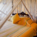 Bedroom with four posted bed and beautiful linen at the Max Wadiya villa. The bedroom has sea views.