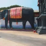 Jaffna Sri Lanka. Sri Lankan girl in a dress walking past a giantblack elephant statue at a temple