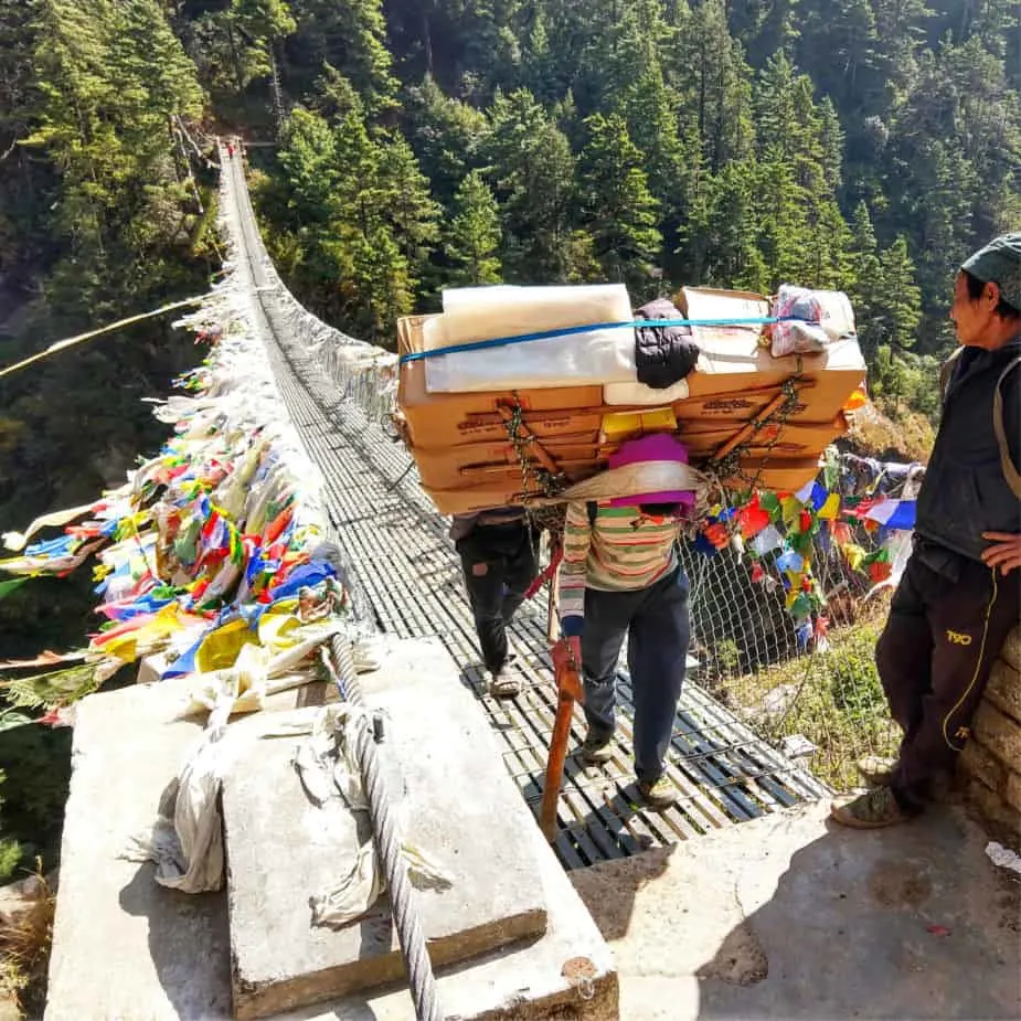 Porter on the Everest Base Camp Trek crossing bridge