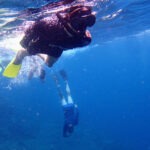 family snorkelling in deep blue water to see manta rays off bali