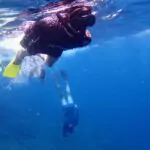 family snorkelling in deep blue water to see manta rays off bali