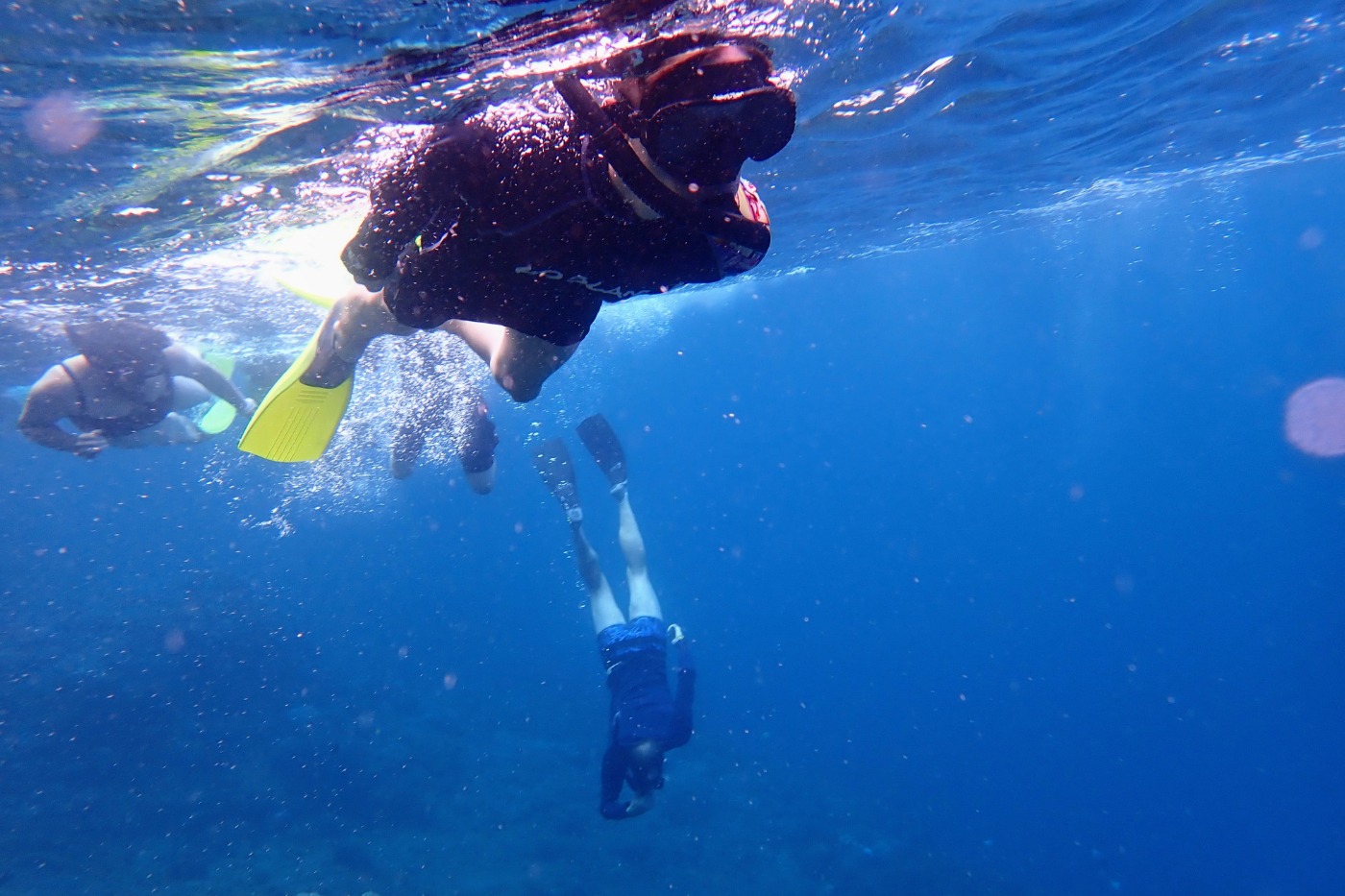 family snorkelling in deep blue water to see manta rays off bali