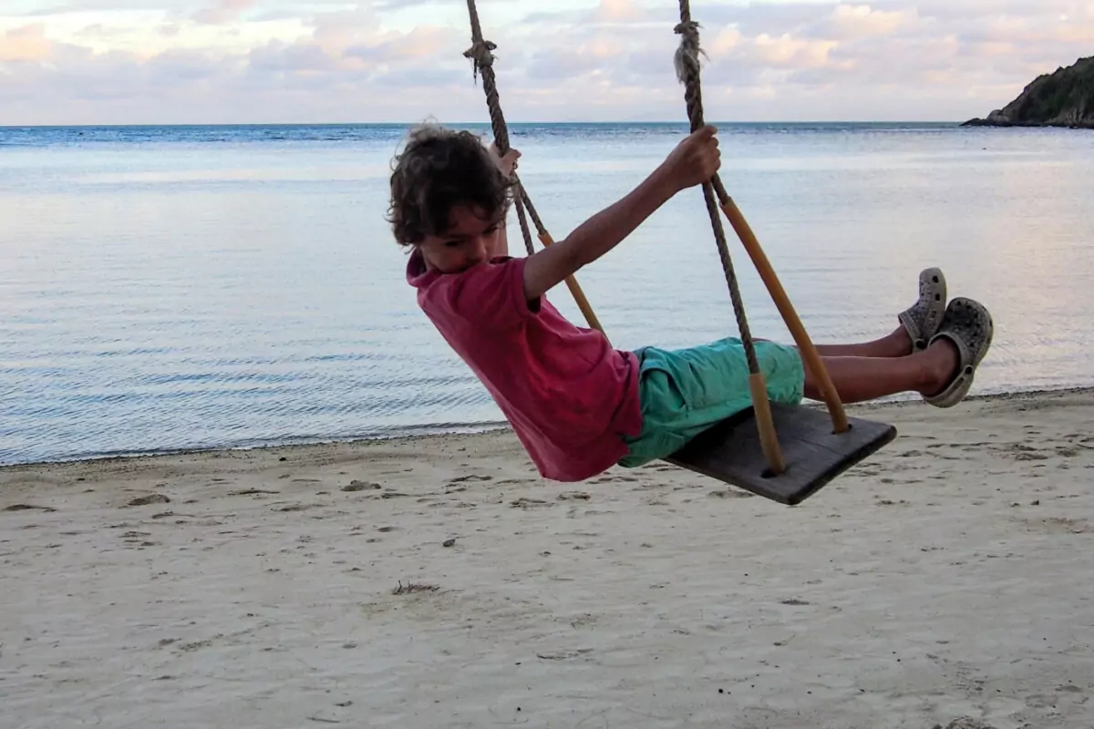 Thailand Western Kid on a beach on a swing