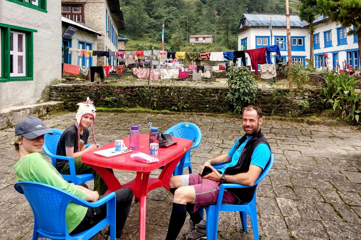 Eating at a tea house in Nepal. Family and 2 kids seated at a table.