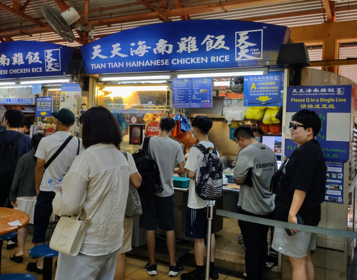 Long queue of people at a hawker food stall selling chicken rice.