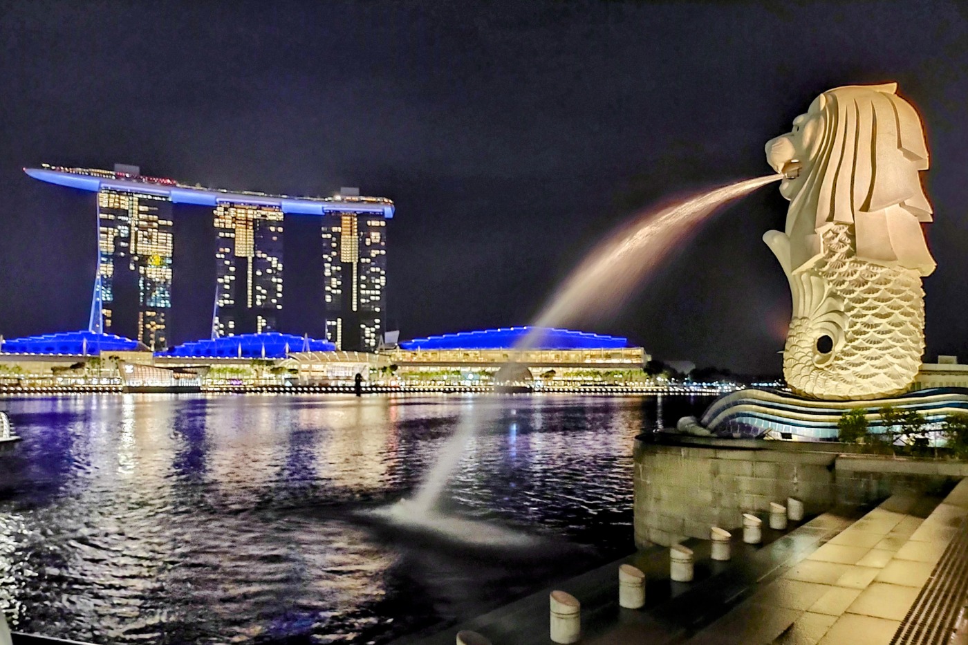 Singapore as a destination. View of Marina Bay Sands and Singapore's Merlion fountain at night.