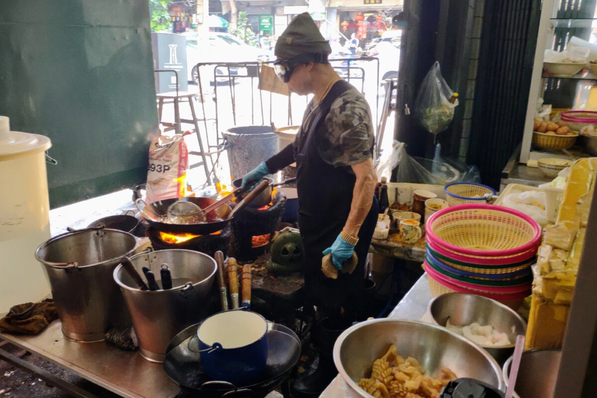 Jay Fai, the cook, cooking at a small gas stove in her Bangkok restaurant.