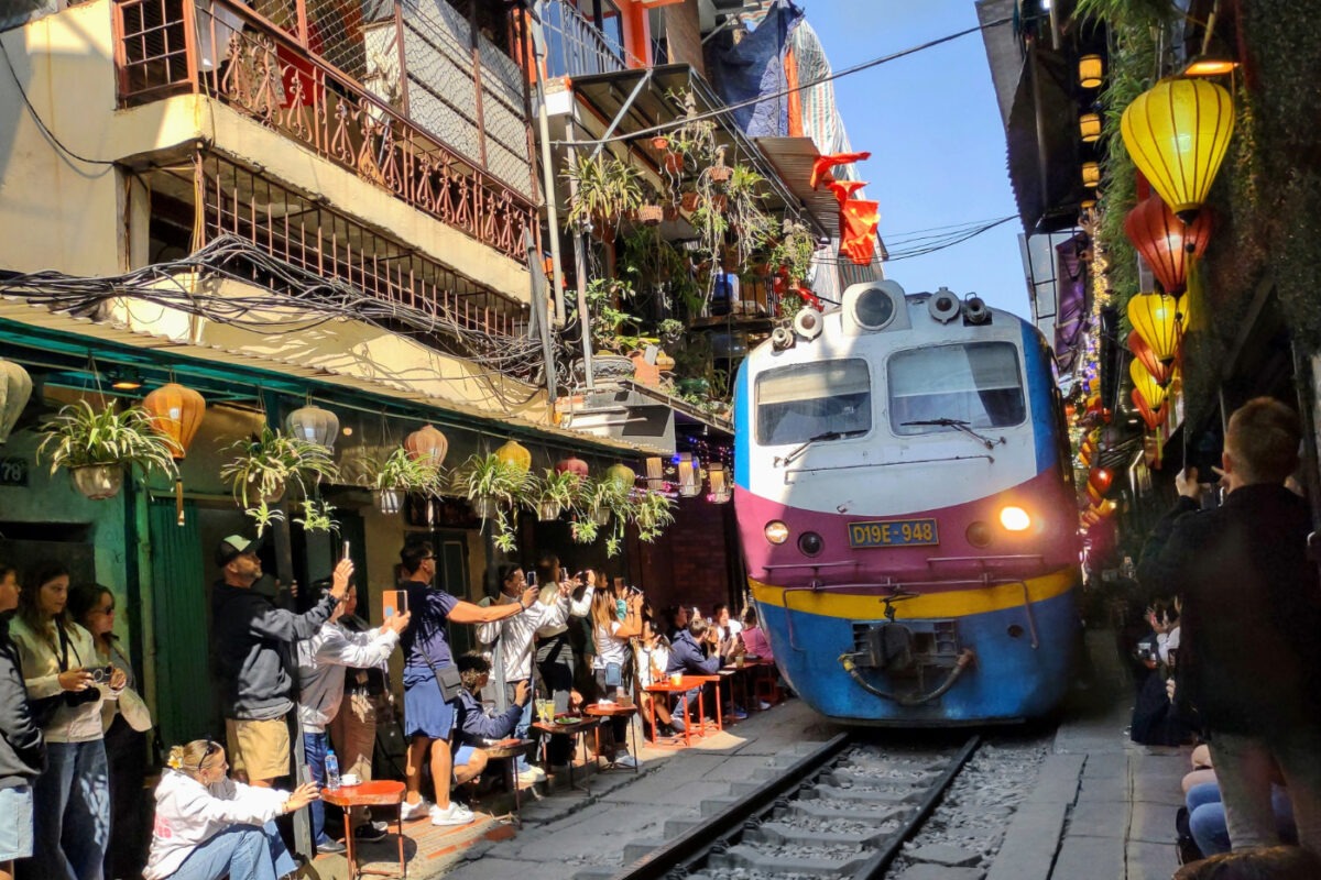 Train passing through busy train street Hanoi